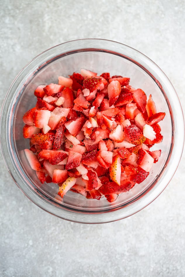 Top view of sliced strawberries in a clear mixing bowl