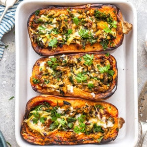 Overhead view of three stuffed butternut squash halves in a baking dish