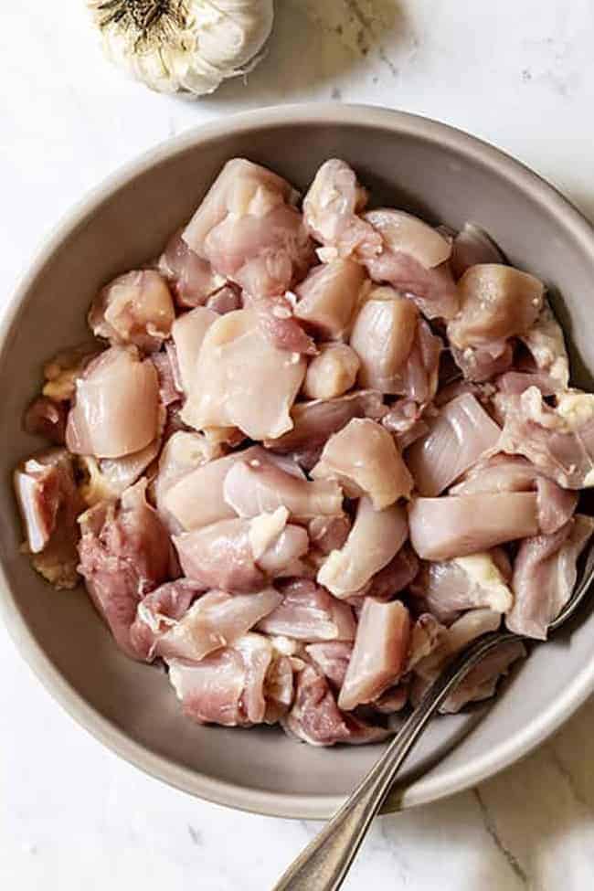 Top view of raw cubed chicken in a grey bowl
