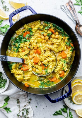 Vegetable noodle soup in a blue dutch oven / pot with a soup ladle