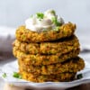 A stack of five healthy zucchini fritters with a seventh one leaning against the stack