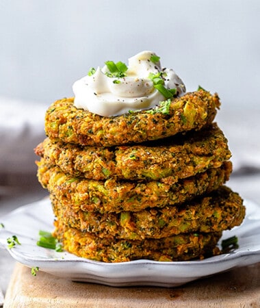 A stack of five healthy zucchini fritters with a seventh one leaning against the stack