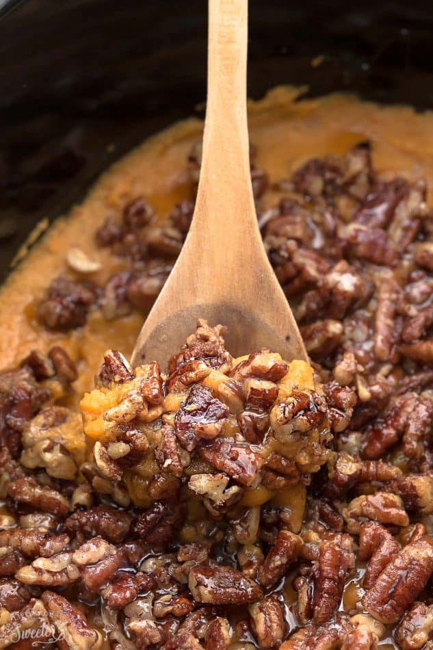 Pecan-topped Sweet Potato Casserole in a slow cooker with a wooden spoon