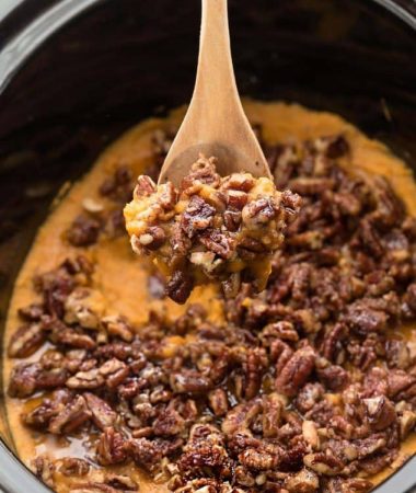Pecan-topped Sweet Potato Casserole in a slow cooker with a wooden spoon