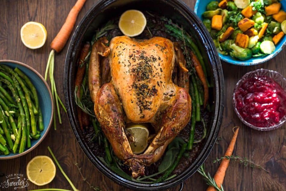 Top view of golden brown Herb Garlic Roasted Turkey in a pan with side dishes