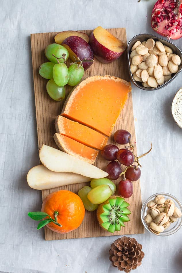 Top view of cheese and fruit on a wooden board