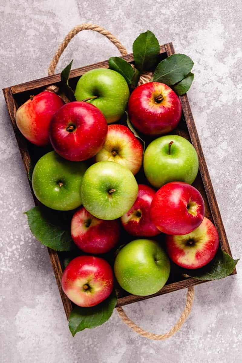Top view of ripe red and green apples in wooden box. 