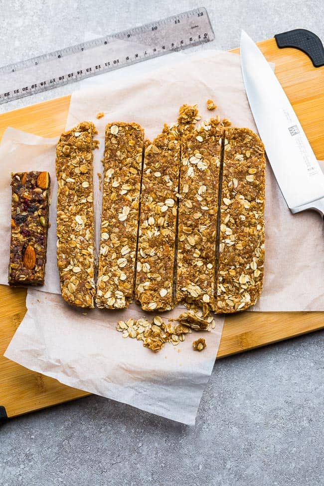 Six granola bars on a cutting board, freshly cut, next to a knife.