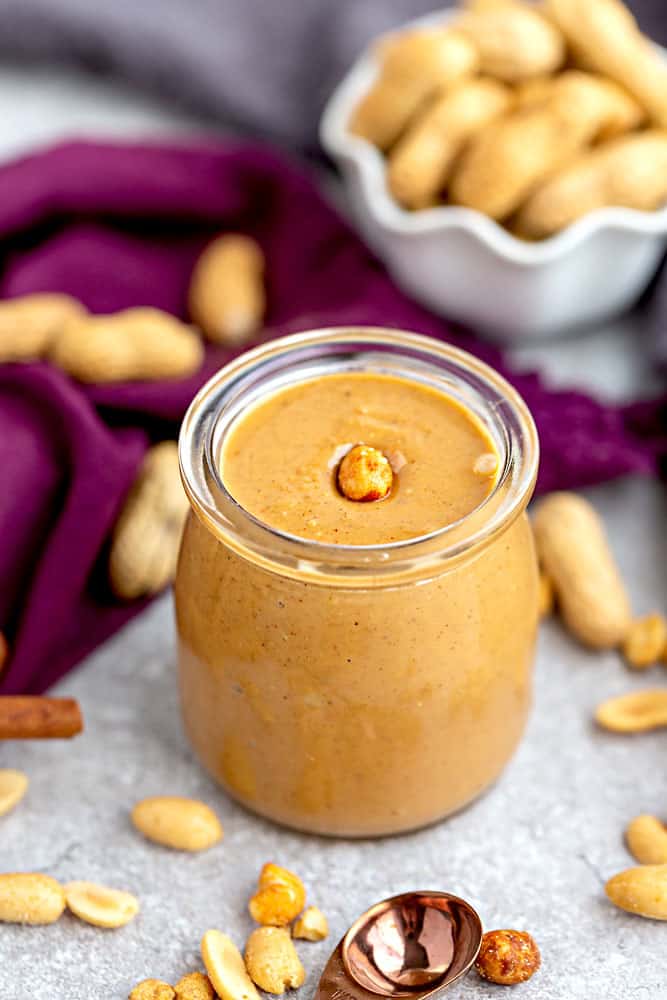 Top view of homemade peanut butter in a jar with a peanut in the jar