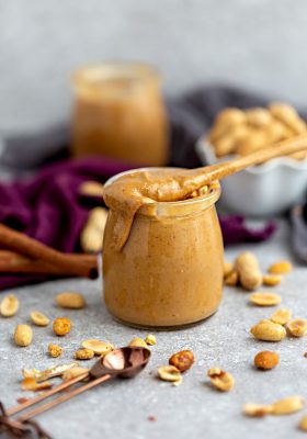 Side view of homemade peanut butter in a jar with a spoon
