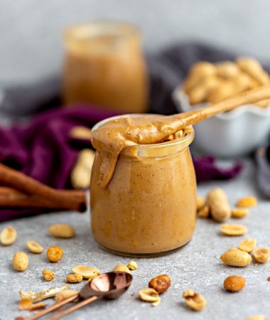 Side view of homemade peanut butter in a jar with a spoon