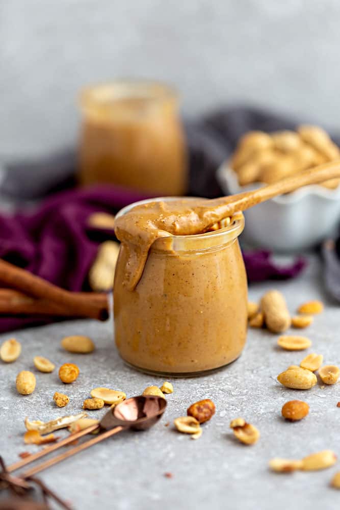 Side view of homemade peanut butter in a jar with a spoon