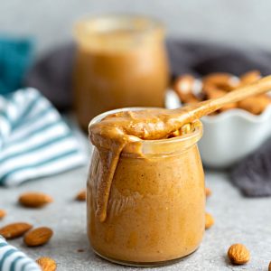 Side view of homemade almond butter in a jar with a spoon