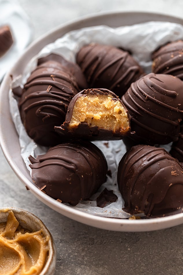 Side shot of a bowl of Reese's peanut butter eggs where one has a bite missing