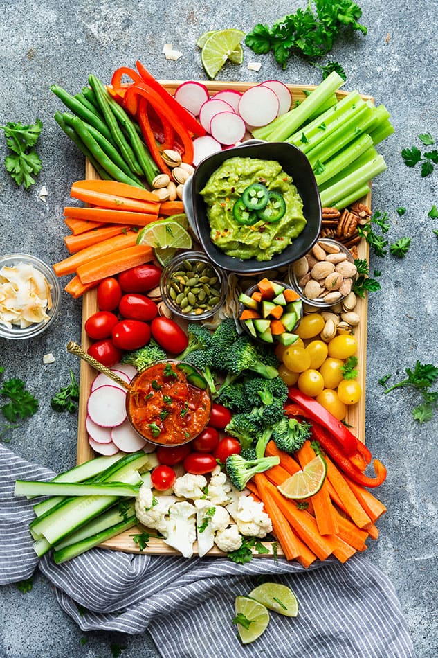 Overhead view of a veggie platter with bowls of guacamole and salsa