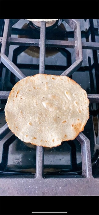 One tortilla shell over a gas burner