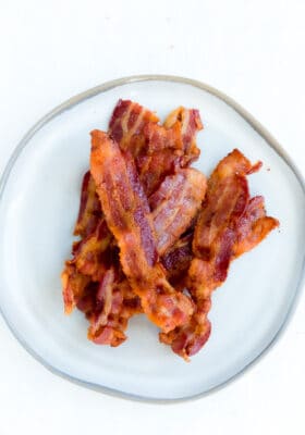 A Pile of Crispy Air Fryer Bacon on a White Plate with a Gray Rim