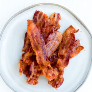 A Pile of Crispy Air Fryer Bacon on a White Plate with a Gray Rim