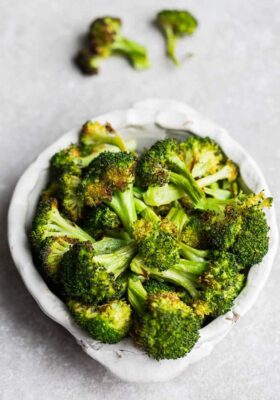 Top view of roasted frozen broccoli in a white bowl