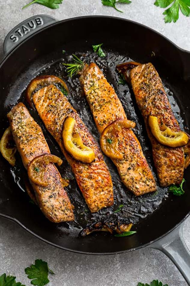 Top view of perfect pan fried salmon in a cast iron skillet with lemon slices