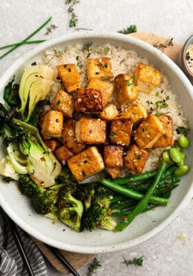 Crispy air-fried tofu in a white bowl with cauilflower rice, broccoli, bok choy and green beans