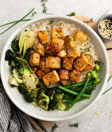 Crispy air-fried tofu in a white bowl with cauilflower rice, broccoli, bok choy and green beans