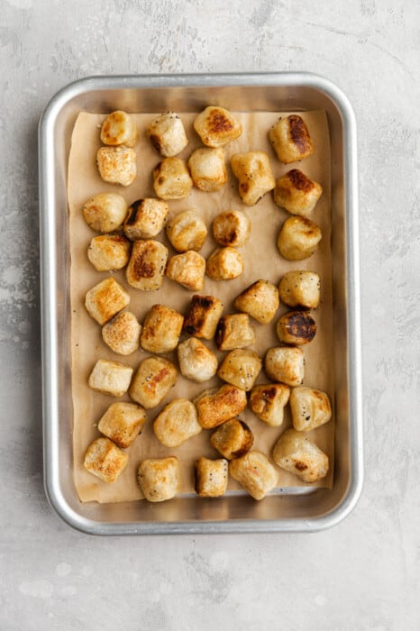 Baked Gnocchi on a Lined Baking Sheet Sitting on a Granite Surface