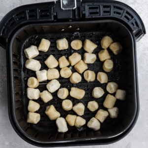 Frozen Cauliflower Gnocchi Inside of an Air Fryer Basket on a Gray Countertop