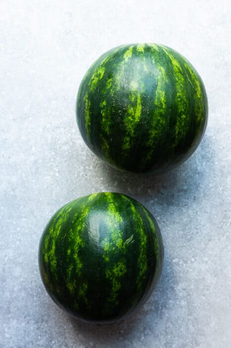 Top view of two mini watermelons on a grey surface