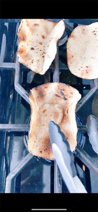 Tongs flipping a charred tortilla shell