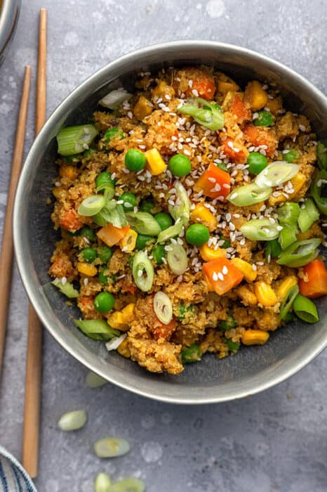 Top view of a bowl of easy cauliflower fried rice in a grey bowl with chopsticks at the side