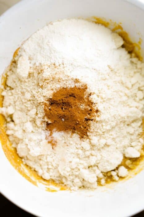 Almond and coconut flours inside of large mixing bowl with cinnamon, baking powder and salt