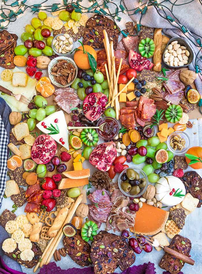 Top view of a holiday cheese board with a variety of crackers, nuts, fruits, meats and cheeses