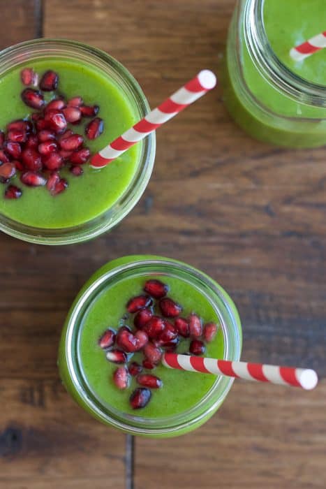 Overhead view of jars of green smoothie topped with pomegranate arils
