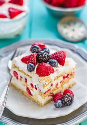 Top view of one slice of icebox cake on a white plate with a fork and mixed berries