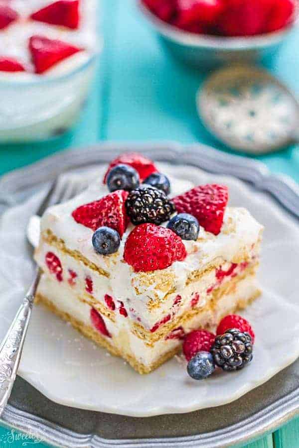 Top view of one slice of icebox cake on a white plate with a fork and mixed berries for berry recipes.