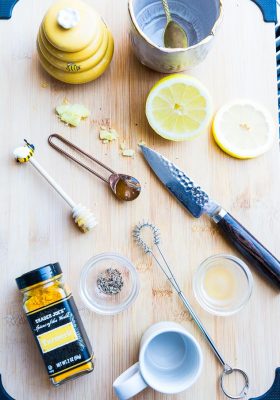 Top view of ingredients to make an immunity boosting shot - turmeric, honey, black pepper, lemon and apple cider vinegar
