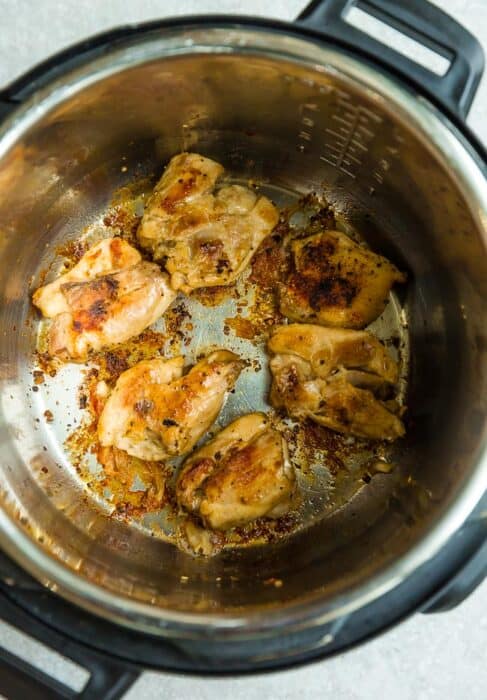 Top view of seared chicken thighs in an Instant Pot pressure cooker instant pot on a grey background