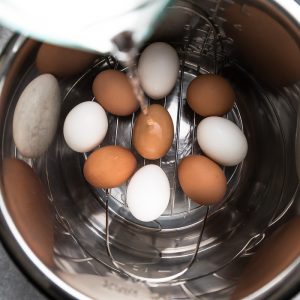 Water Being Poured Into an Instant Pot Filled with Large Eggs