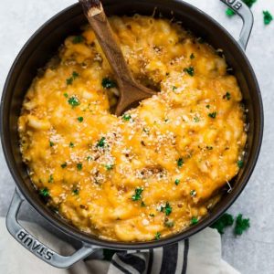 Top view of a pot of instant pot macaroni and cheese in a cast iron pot with a wooden spoon