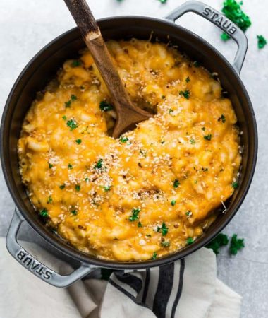 Top view of a pot of instant pot macaroni and cheese in a cast iron pot with a wooden spoon