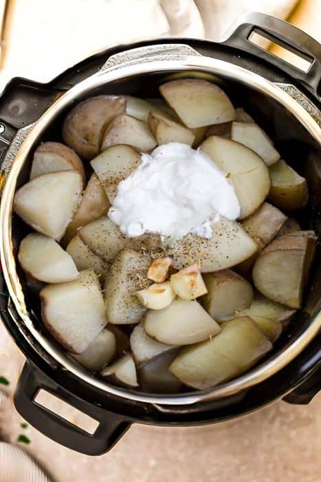 Top view of cut Russet potatoes and garlic in a pressure cooker