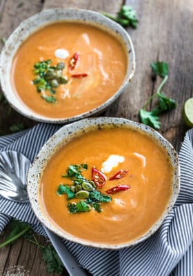 Top view of two bowls of instant pot pumpkin soup garnished with pepitas and coconut cream