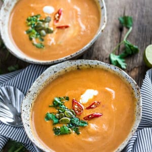 Top view of two bowls of instant pot pumpkin soup garnished with pepitas and coconut cream