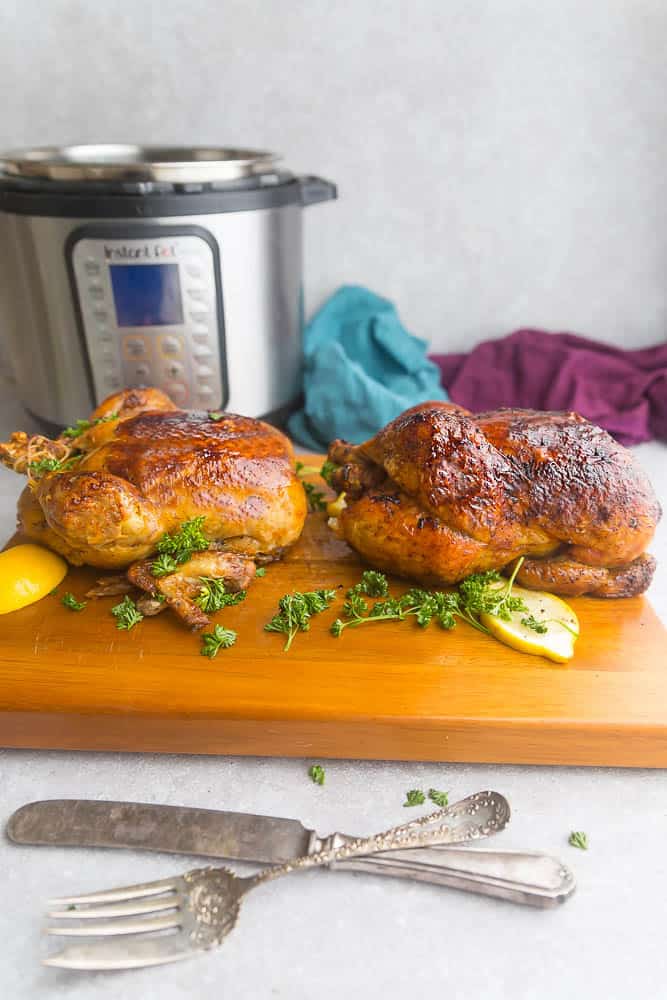 two whole rotisserie style chickens sitting on a cutting board next to the Instant Pot pressure cooker they were cooked in