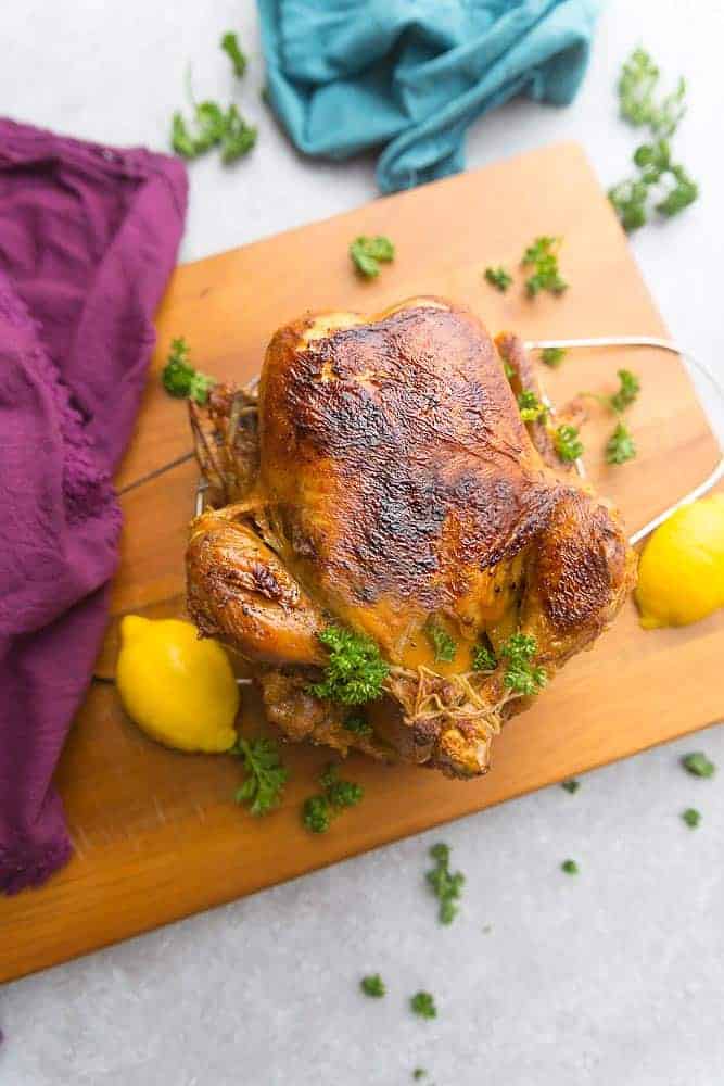 golden crispy skinned whole chicken cooked in an Instant Pot sitting on a cutting board