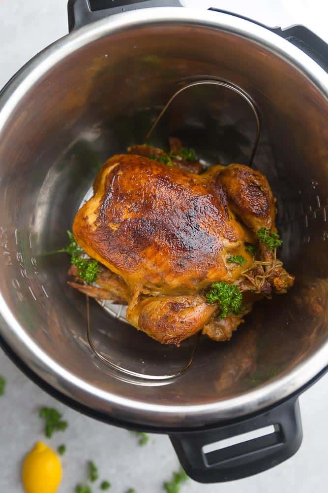 beautifully golden brown whole chicken sitting in an Instant Pot