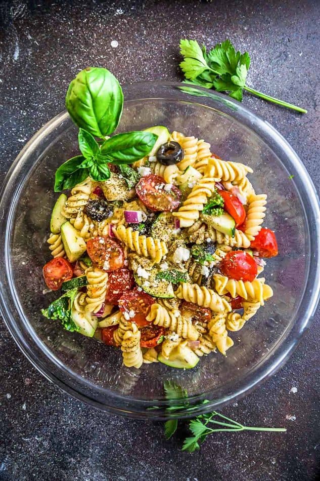 This Easy Italian Pasta is the perfect side dish for summer barbecues, potlucks, parties and cookouts. Best of all, you can customize the add-ins with what you have on hand. This recipe includes cherry tomatoes, zucchini, olives, feta cheese, onions, chopped kale and some fresh herbs like parsley and basil. A homemade Italian dressing makes this even more delicious!