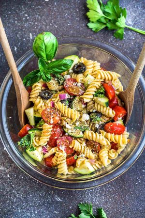 This Easy Italian Pasta is the perfect side dish for summer barbecues, potlucks, parties and cookouts. Best of all, you can customize the add-ins with what you have on hand. This recipe includes cherry tomatoes, zucchini, olives, feta cheese, onions, chopped kale and some fresh herbs like parsley and basil. A homemade Italian dressing makes this even more delicious!