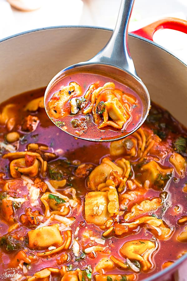 Overhead view of Italian Sausage Tortellini Tomato Soup in a pot with a ladle taking a scoop